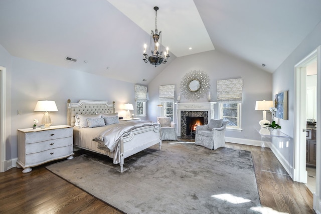 bedroom featuring a high end fireplace, visible vents, baseboards, vaulted ceiling, and dark wood-style floors