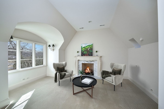 sitting room featuring visible vents, carpet flooring, a high end fireplace, and vaulted ceiling