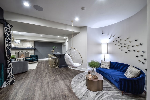 living room featuring recessed lighting, baseboards, a stone fireplace, and wood finished floors