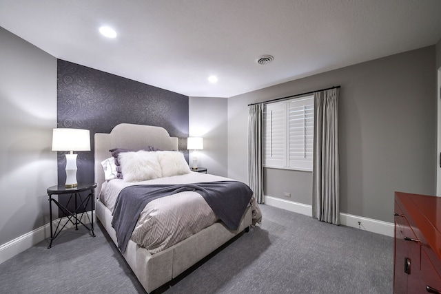 bedroom featuring visible vents, baseboards, carpet, and an accent wall