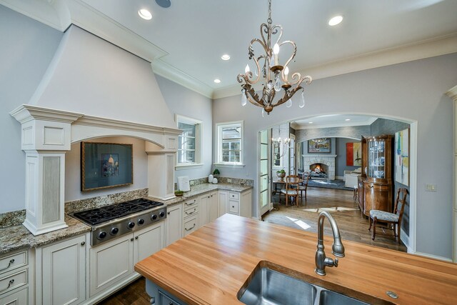 kitchen with crown molding, stainless steel gas stovetop, a notable chandelier, and wood counters