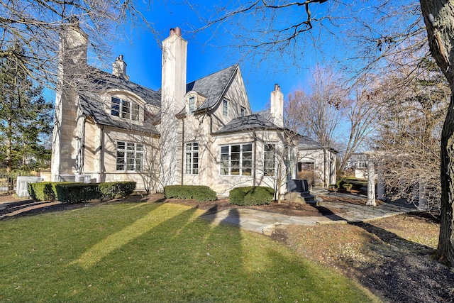 rear view of property featuring a high end roof, a yard, and a chimney