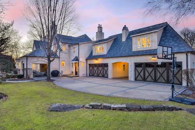 view of front of property with stucco siding, concrete driveway, a chimney, and a front yard