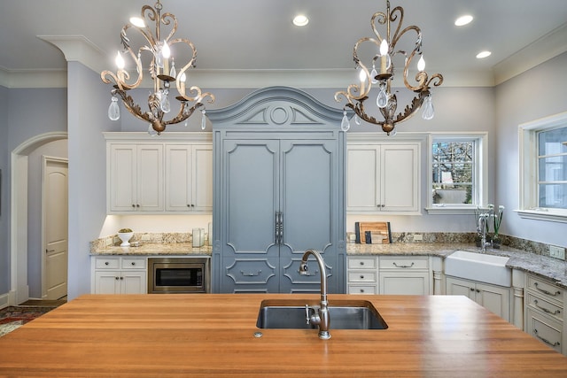 kitchen featuring stainless steel microwave, wooden counters, and a sink