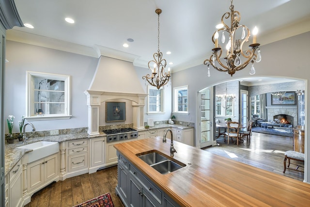 kitchen with a fireplace, wood counters, an inviting chandelier, and a sink