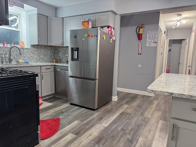 kitchen with wood finished floors, tasteful backsplash, appliances with stainless steel finishes, and gray cabinetry