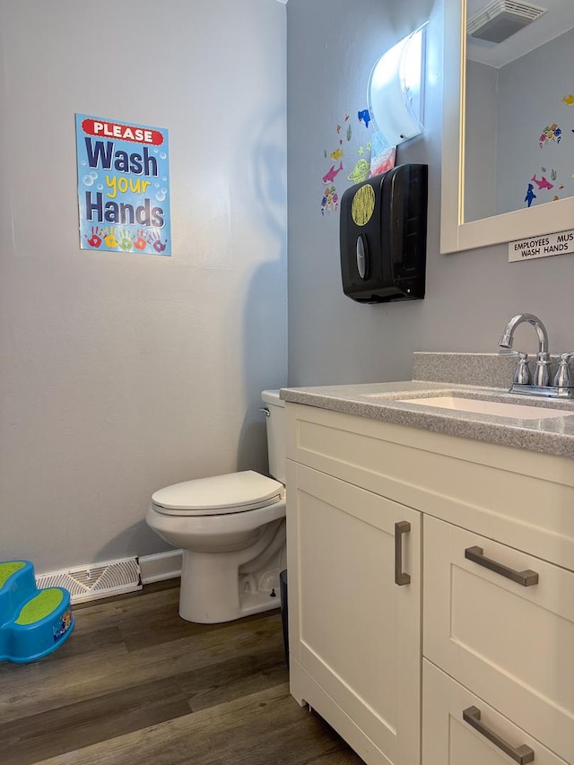 bathroom featuring vanity, toilet, wood finished floors, and visible vents