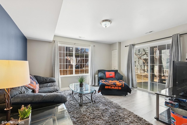 living room featuring visible vents, a healthy amount of sunlight, and wood finished floors