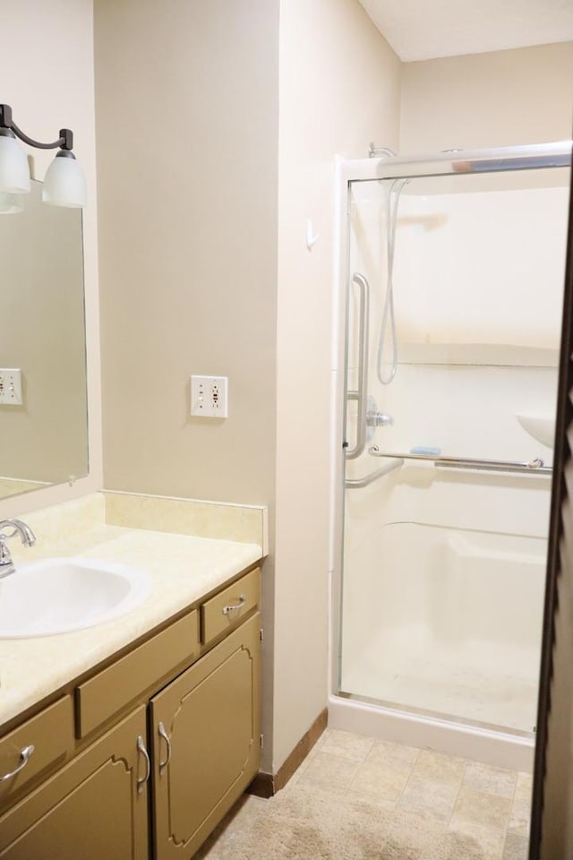 bathroom with baseboards, vanity, and a shower stall