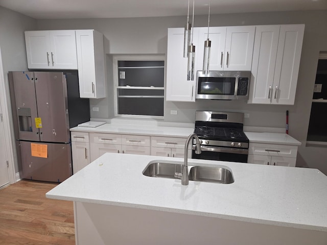 kitchen featuring white cabinets, appliances with stainless steel finishes, light wood-type flooring, and a sink