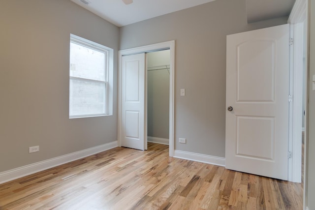 unfurnished bedroom with baseboards, a closet, and light wood-type flooring