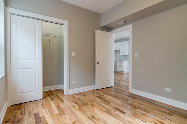 unfurnished bedroom featuring visible vents, light wood-type flooring, a closet, and baseboards