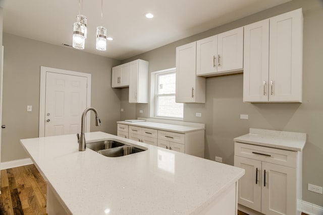 kitchen with a center island with sink, a sink, recessed lighting, white cabinets, and baseboards