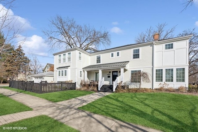 view of front facade featuring fence, a porch, a front yard, metal roof, and a chimney