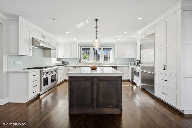 kitchen with under cabinet range hood, a kitchen island, white cabinets, light countertops, and built in appliances