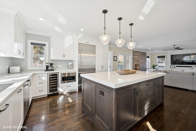 kitchen featuring stainless steel appliances, beverage cooler, ornamental molding, and white cabinetry