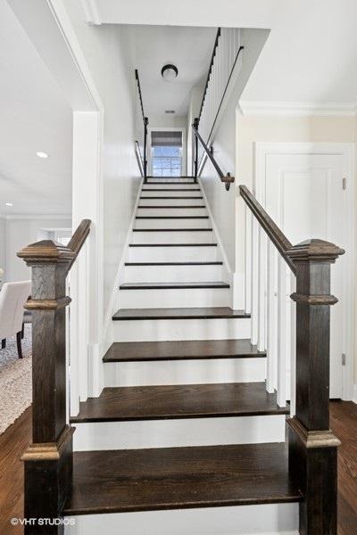 staircase featuring wood finished floors and crown molding