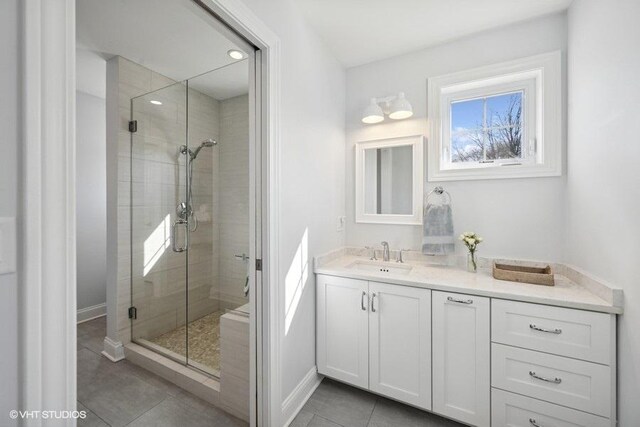 bathroom featuring baseboards, vanity, a shower stall, and tile patterned flooring