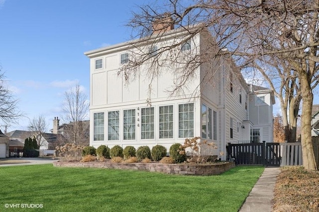 view of side of home with a yard, fence, and a chimney