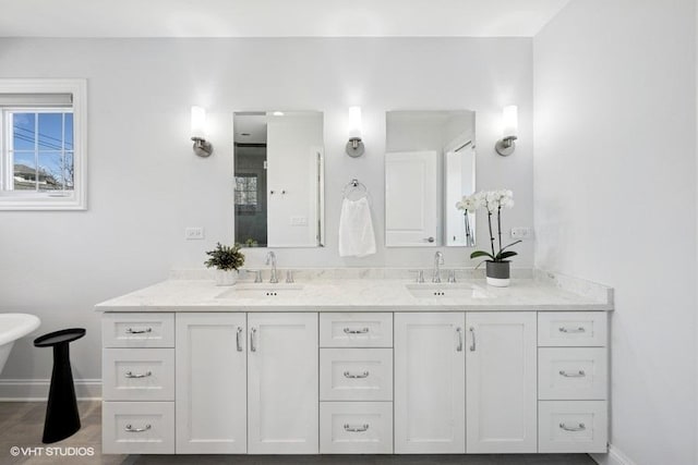 bathroom featuring a sink, baseboards, and double vanity