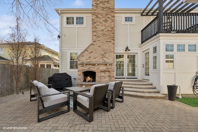 view of patio featuring an outdoor living space with a fireplace, area for grilling, a balcony, and fence