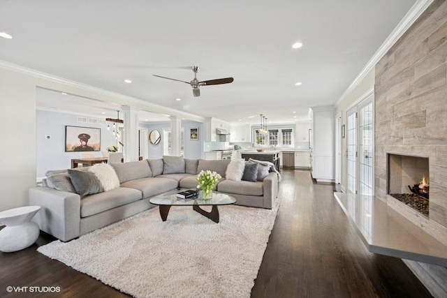 living room featuring dark wood-style floors, a tiled fireplace, and ornamental molding