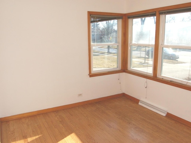 empty room with light wood-type flooring, visible vents, and baseboards