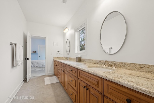 ensuite bathroom with double vanity, baseboards, a sink, and tile patterned floors