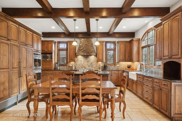 kitchen with tasteful backsplash, an island with sink, custom range hood, appliances with stainless steel finishes, and a sink