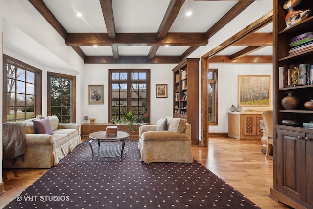 living area featuring light wood-style flooring, baseboards, and beam ceiling