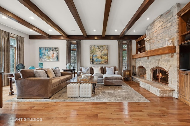 living area featuring light wood-style floors, a fireplace, and beam ceiling