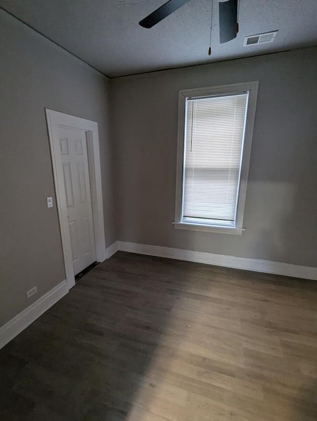 unfurnished room with visible vents, baseboards, ceiling fan, and wood finished floors