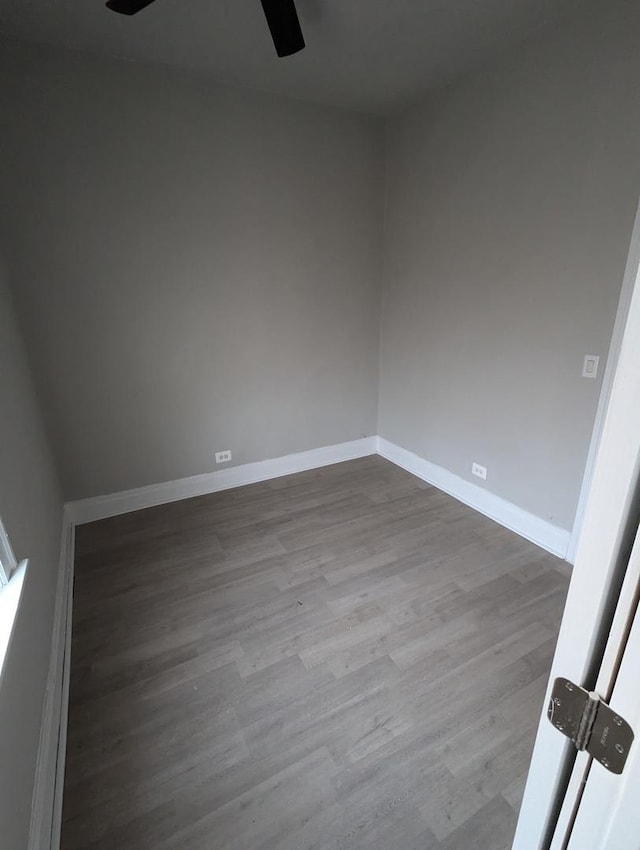 unfurnished room with a ceiling fan, baseboards, and dark wood-style flooring