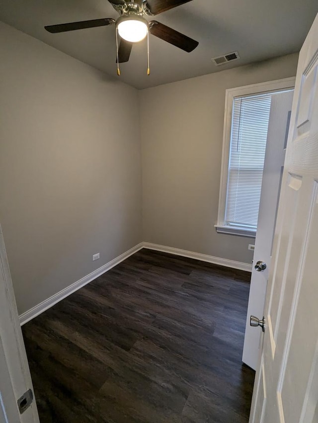 spare room with dark wood-style floors, visible vents, a ceiling fan, and baseboards