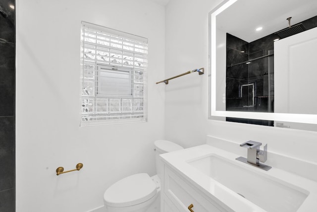 bathroom with a tile shower, toilet, and vanity