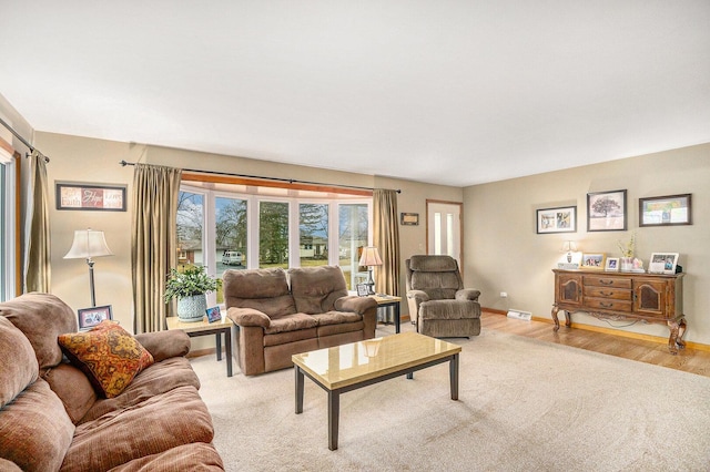 living area featuring visible vents, light wood-type flooring, and baseboards