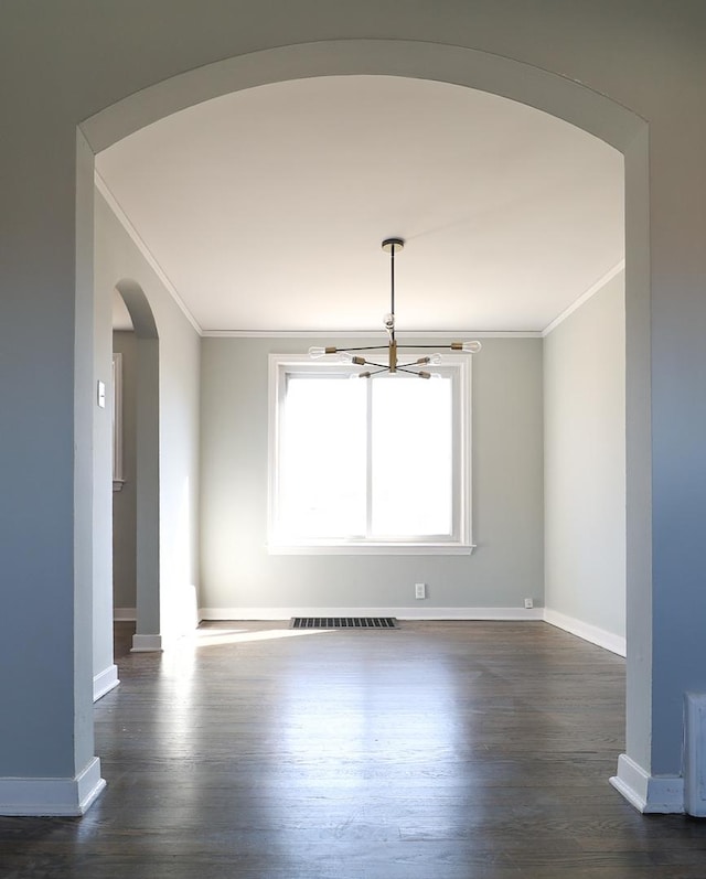 empty room with visible vents, ornamental molding, dark wood finished floors, arched walkways, and baseboards