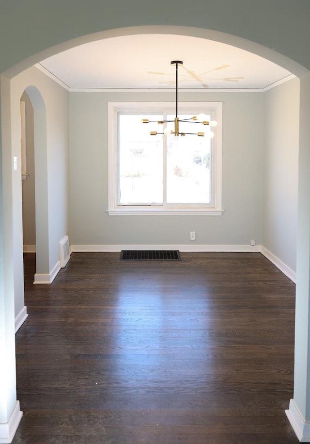 spare room with arched walkways, crown molding, visible vents, wood finished floors, and baseboards