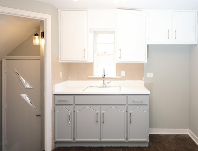 kitchen with baseboards, light countertops, a sink, and decorative backsplash