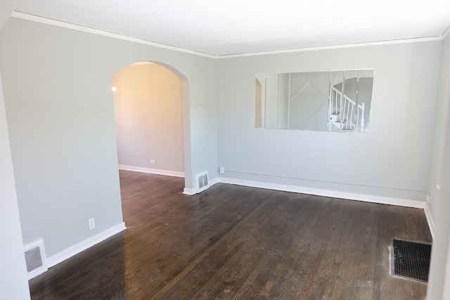 spare room with arched walkways, wood finished floors, visible vents, and baseboards