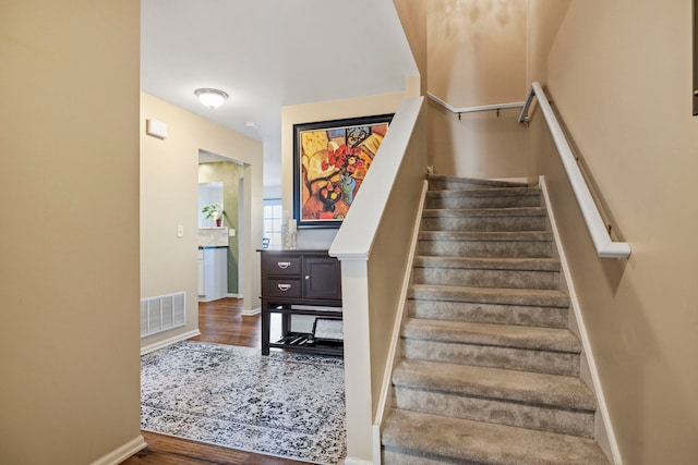 stairway with visible vents, baseboards, and wood finished floors