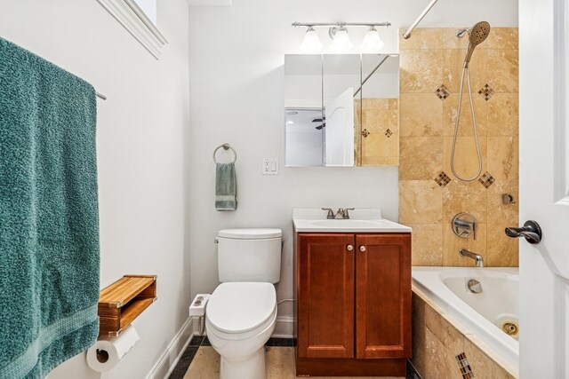 bathroom with vanity, toilet, baseboards, and tiled shower / bath combo