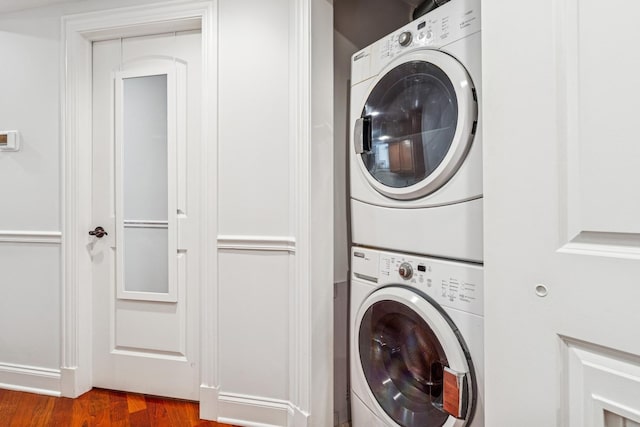 laundry area featuring laundry area, stacked washer and clothes dryer, and wood finished floors