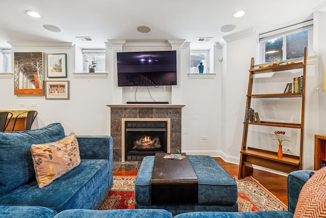 living room with visible vents, wood finished floors, crown molding, a premium fireplace, and baseboards