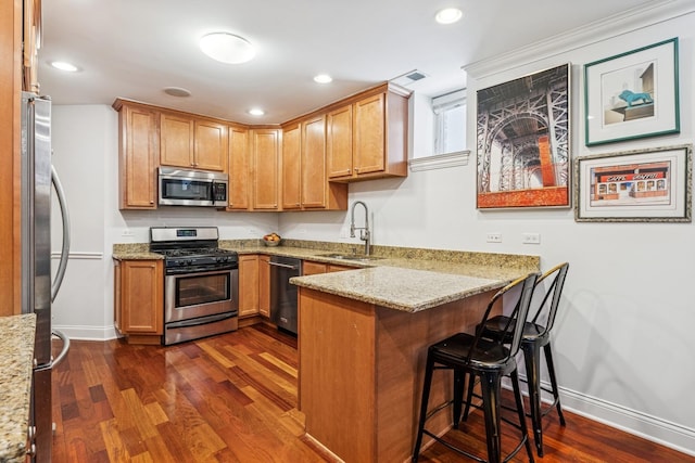 kitchen featuring visible vents, dark wood-type flooring, appliances with stainless steel finishes, a peninsula, and a sink