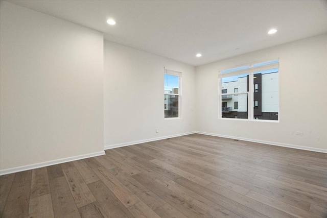 spare room featuring baseboards, wood finished floors, and recessed lighting