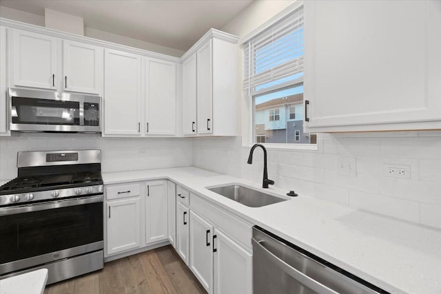 kitchen featuring light countertops, appliances with stainless steel finishes, a sink, and white cabinetry