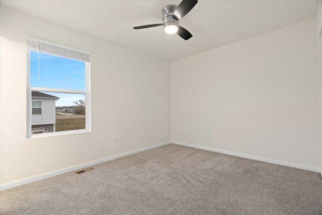 empty room with visible vents, carpet flooring, a ceiling fan, and baseboards