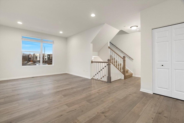 unfurnished living room with baseboards, wood finished floors, stairs, and recessed lighting