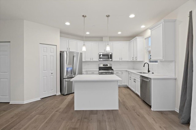 kitchen with stainless steel appliances, white cabinetry, and light wood-style flooring